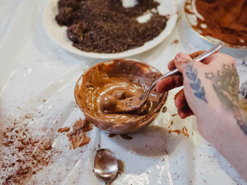 A glass bowl full of melted milk chocolate with cocoa around it